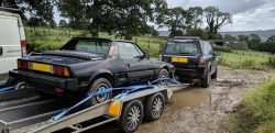 Fiat X1/9 on trailer behind a Land Rover